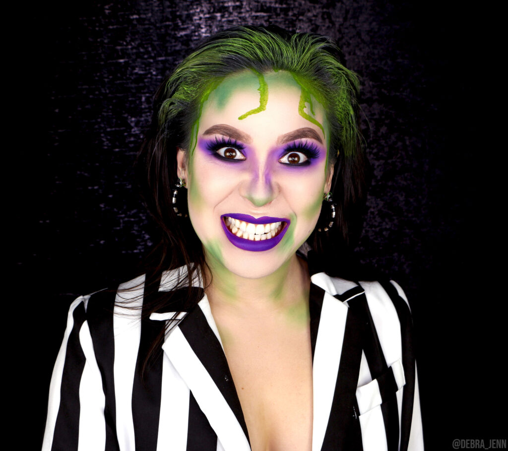 scary beetlejuice makeup with purple eyeshadow and lips and green hair with green dripping around face