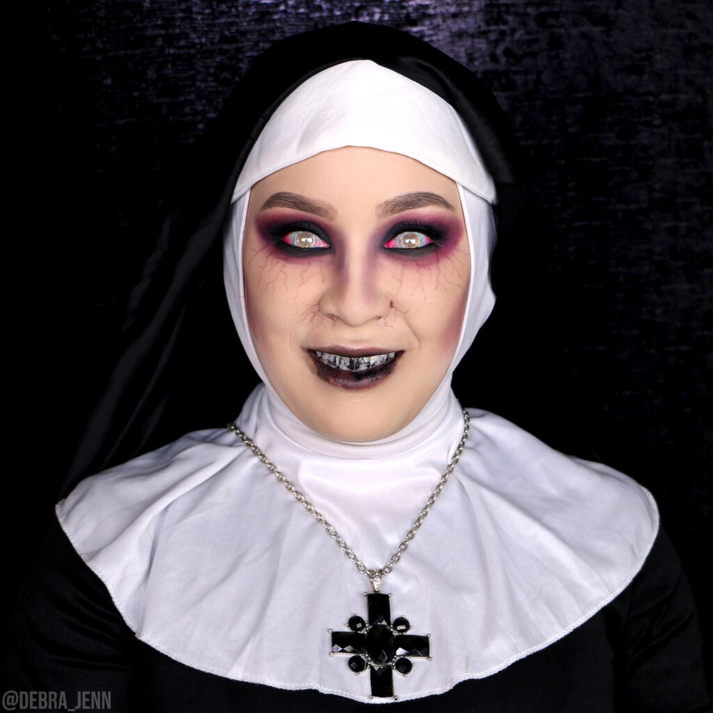 the nun makeup for a scary halloween costume with black, veiny eyes, black teeth, and glowing eyes