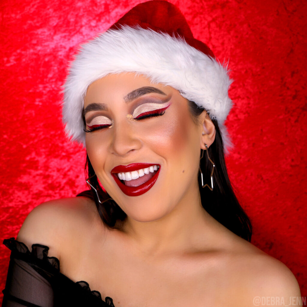 Debra Jenn in the perfect christmas cut crease with brown and sparkly white cut crease, red winged eyeliner, and glossy red lips