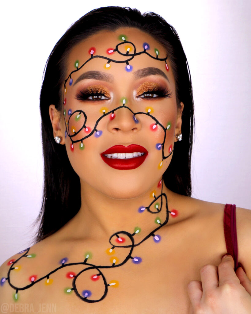 Debra Jenn in christmas lights makeup with gold eyeshadow and christmas lights string drawn on face and neck
