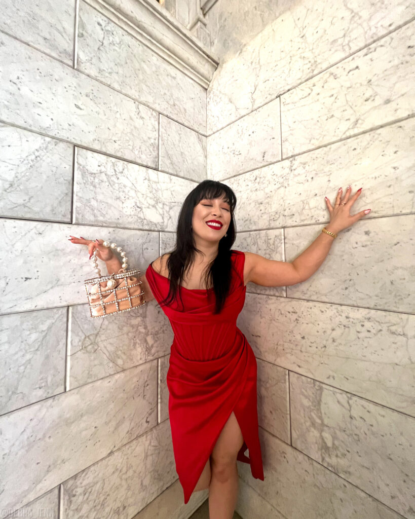 Debra Jenn showing off Rosantica Bag Dupe wearing red satin dress from House of CB